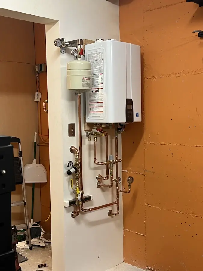 Plumbing technician inspecting water heater connections in Heeia